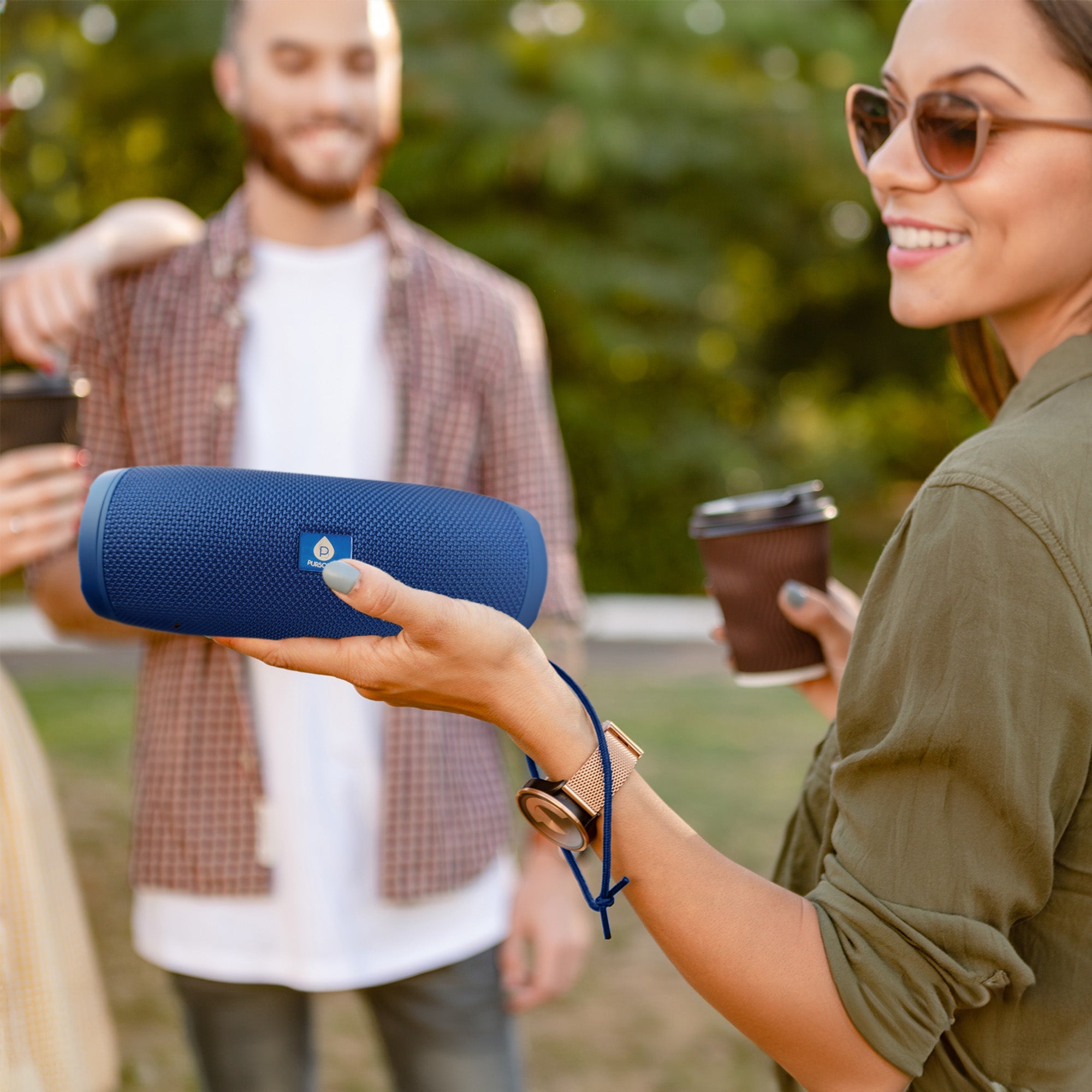 Blue portable wireless speaker held in hand, cylindrical mesh grille