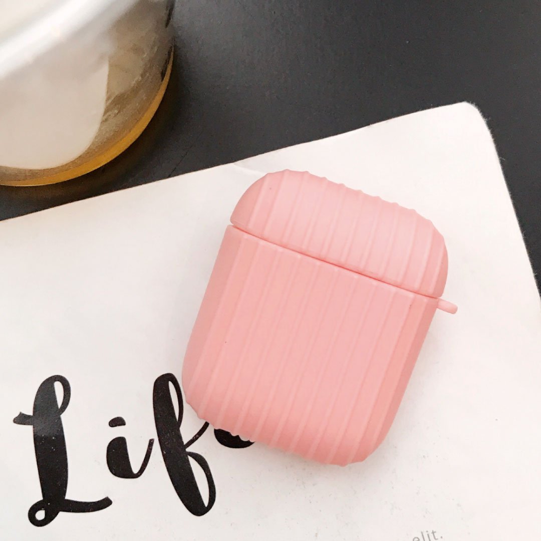 Pink ribbed AirPod case with small side handle on a white surface