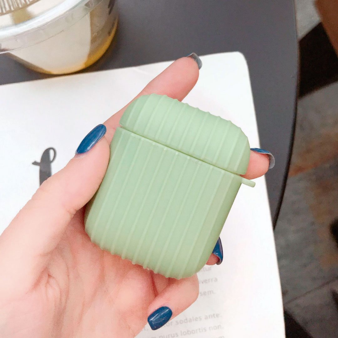Light green ribbed AirPod case with small side handle, held in a hand