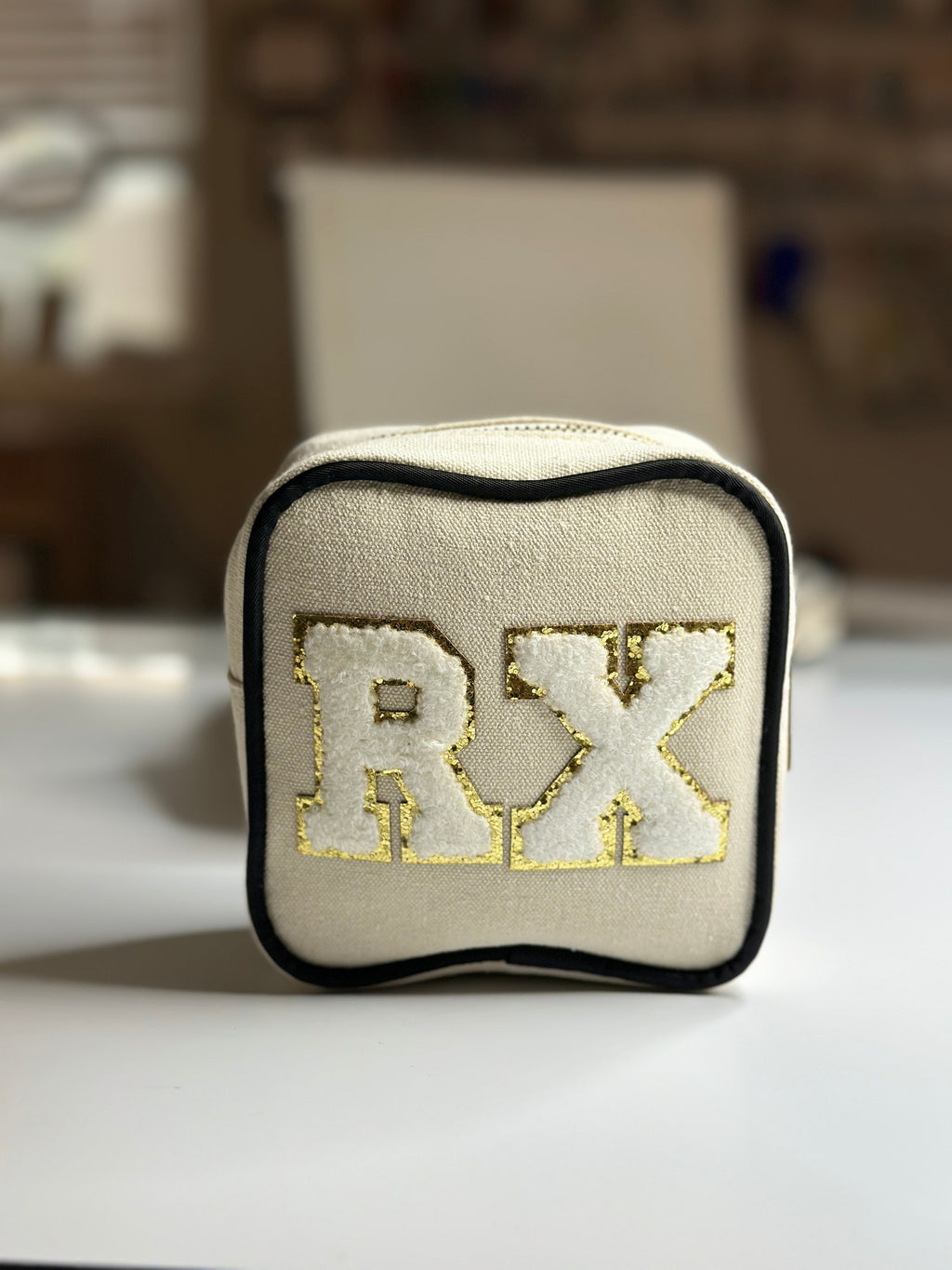 Square zip pouch with embroidered initials on beige fabric and black trim