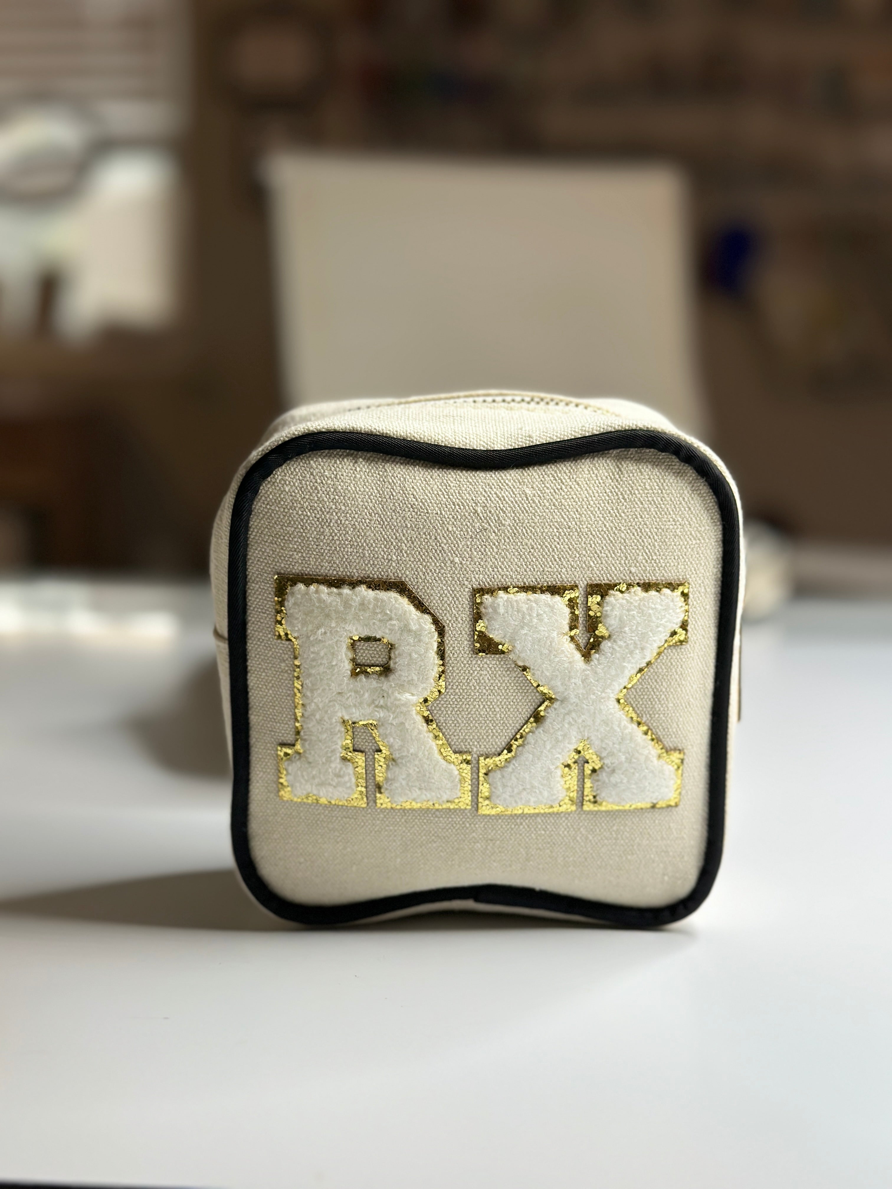 Square zip pouch with embroidered initials on beige fabric and black trim